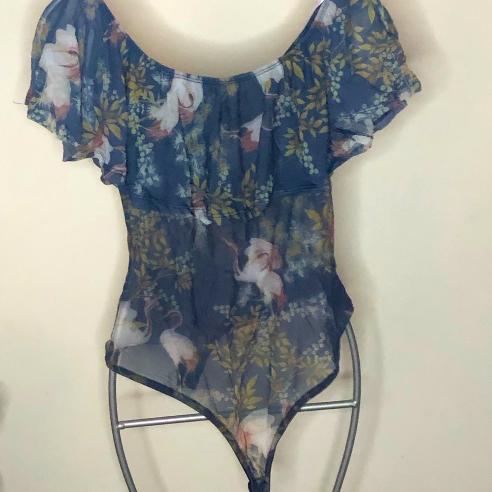 A’gaci Med
blue flowered body suit w/ ruffle collar Snap crotch. New never worn